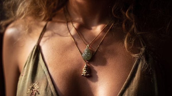 Una persona usando dos collares de Buda, uno de oro y otro de jade, con una expresión serena.