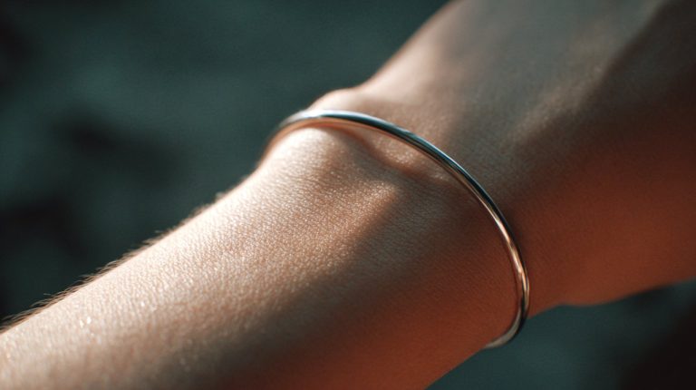 A simple, elegant silver bracelet on a wrist, with soft, natural lighting.
