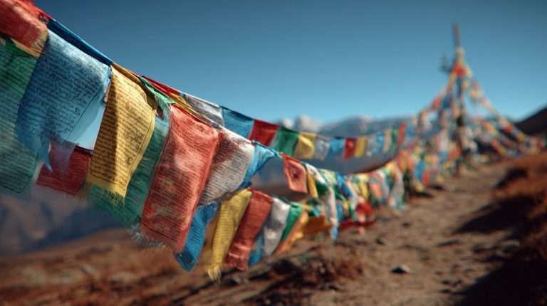 Vibrant Sanskrit prayer flags fluttering on a mountain pass.